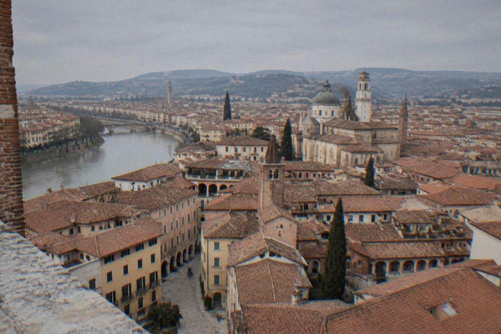 The view from a high tower terrace over the red rooftops and church domes of Verona with hills on the horizon