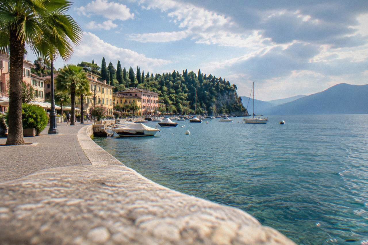 Lakeside promenade in Bardolino with palm trees and boats on Lake Garda