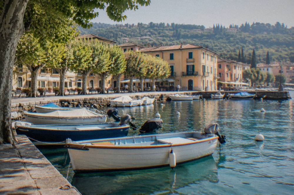 Harbour in Bardolino with moored small boats and ochre buildings behind