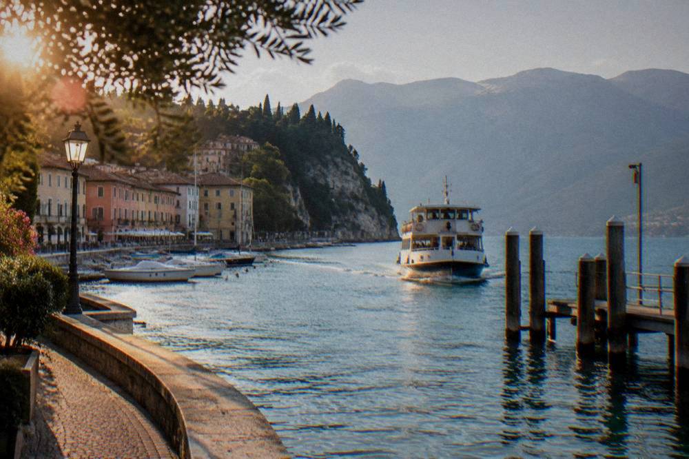 White ferry boat approaching a wooden pier on Lake Garda