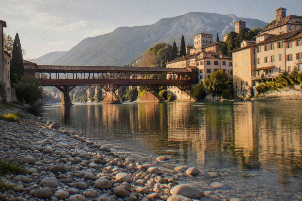 The wooden covered bridge seen from a pebble riverbank with mountains in the background