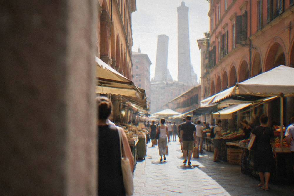 A busy Bologna food market street with awnings, counters and shoppers carrying paper bags