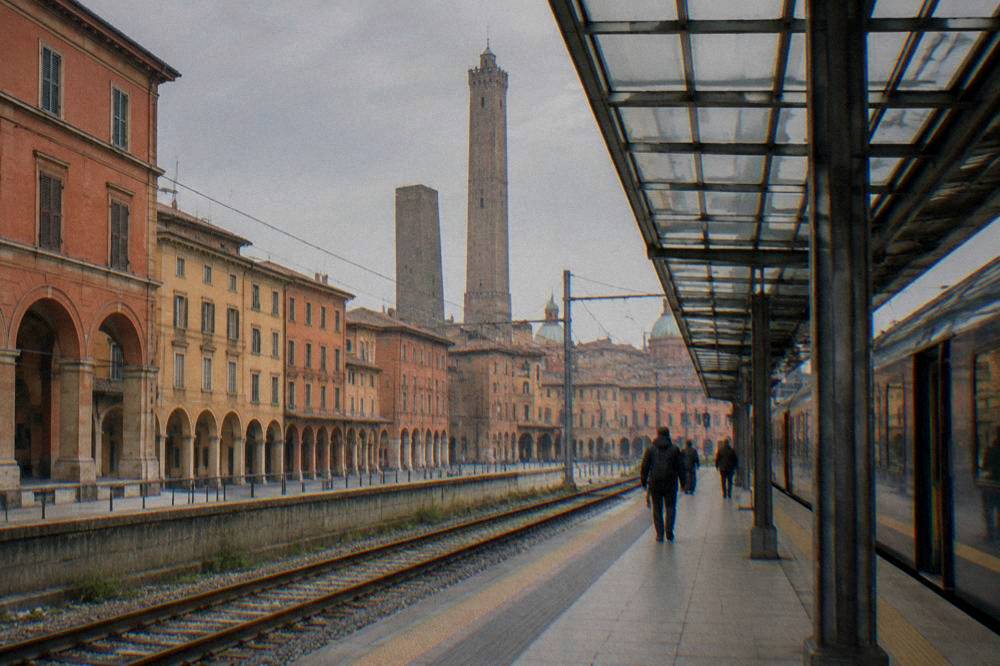 A regional train waiting at a platform under a glass station roof in northern Italy