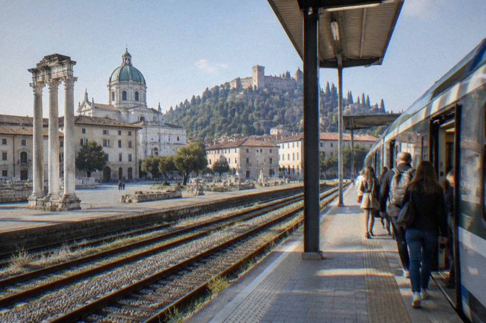 A regional train waiting at an Italian station platform with passengers boarding