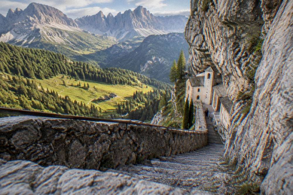 A narrow stone staircase descending a cliff face toward a sanctuary built into the rock