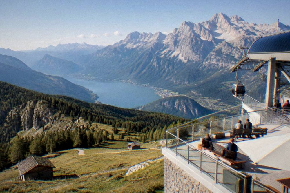 A cable car station terrace with a panoramic view over a blue lake and distant peaks