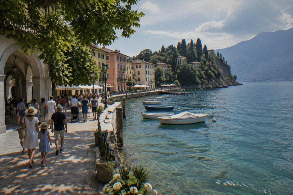 Families walking along a shaded promenade near the Lake Garda shore in summer