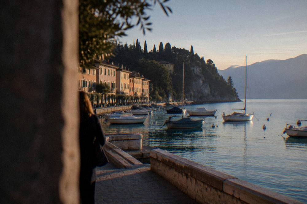 Evening light over a Lake Garda harbour with boats at their moorings and hills in silhouette