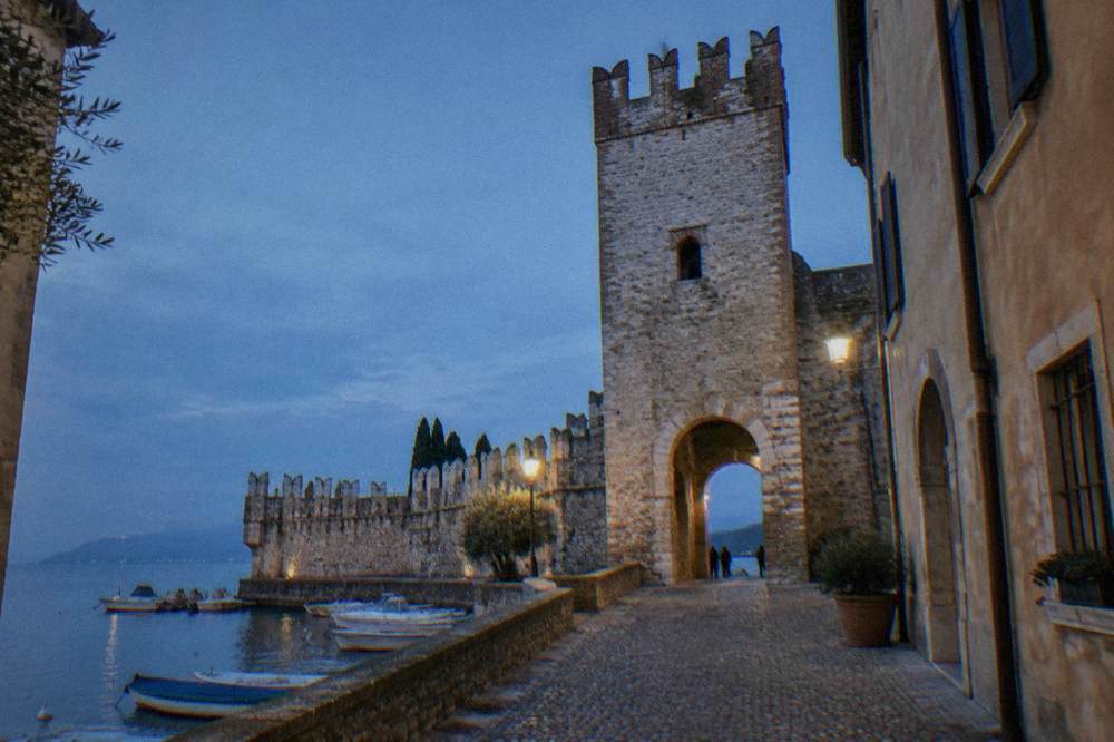 A stone gate tower of the medieval walls in Lazise seen from a narrow street