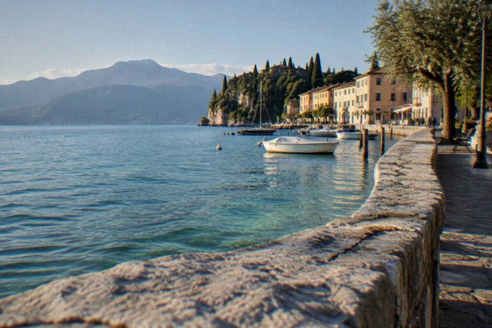 View across Lake Garda from the shore path at Lazise toward the western hills