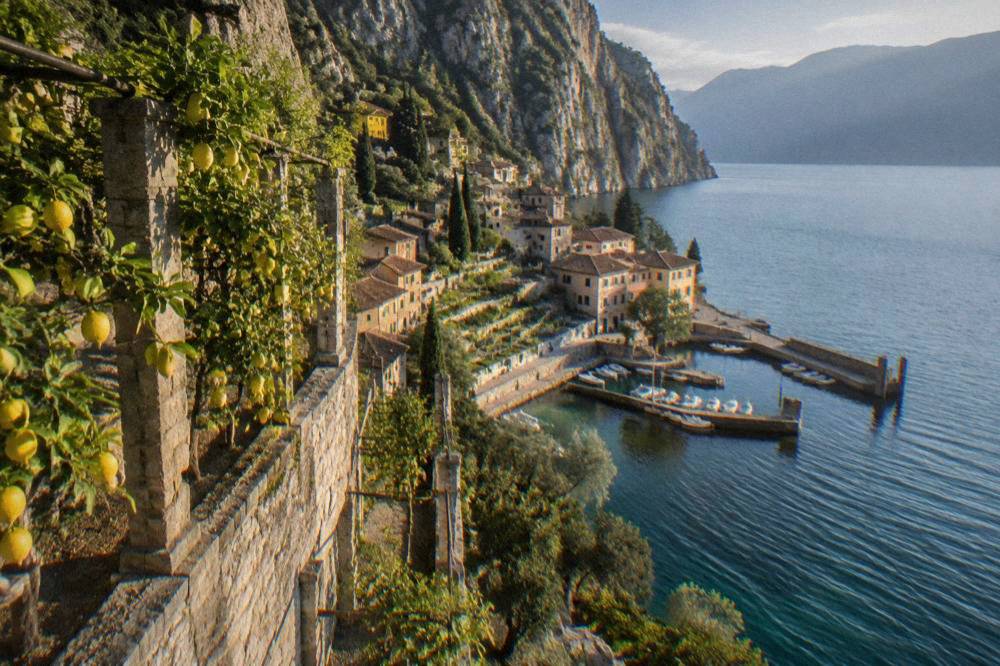 Rows of lemon trees growing inside a tall stone terrace frame beside a lake