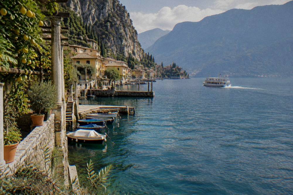 A white passenger ferry crossing a wide blue mountain lake towards a small harbour town