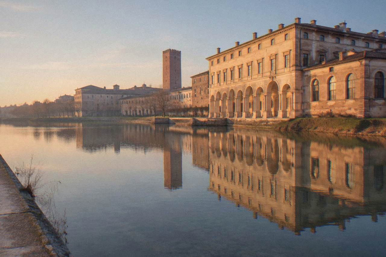 A Renaissance palace facade reflected in a calm lake at golden hour