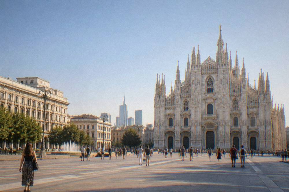 A grand marble cathedral facade rising above a large open square