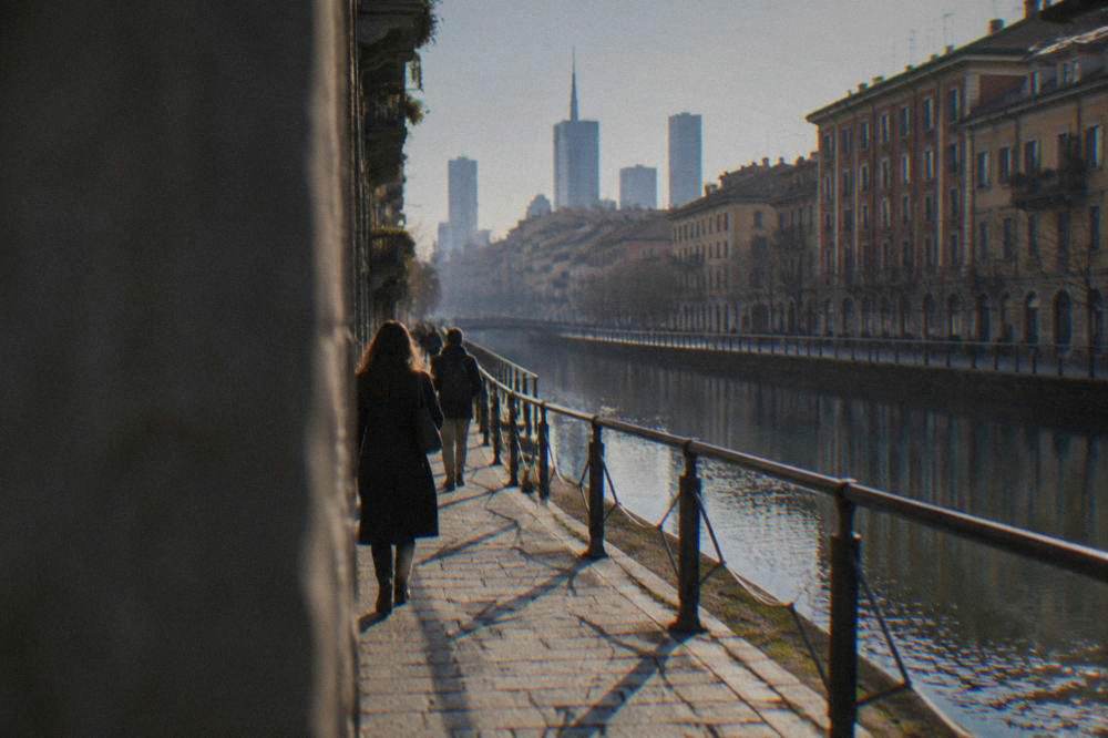 People walking along a canal-side street lined with old brick buildings