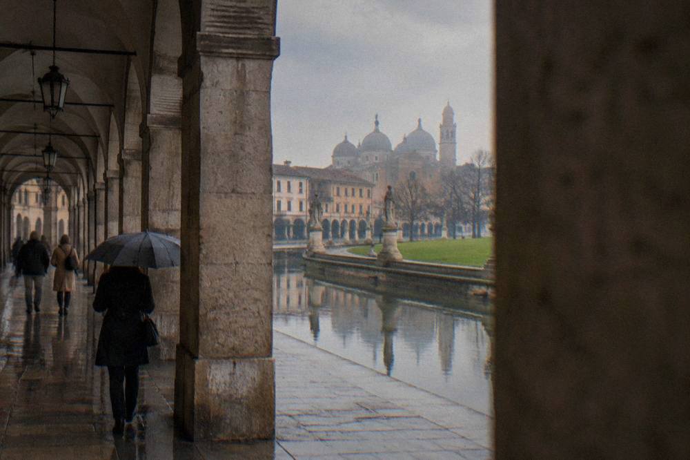An arcaded street in Padua's historic centre with people walking under medieval stone arches