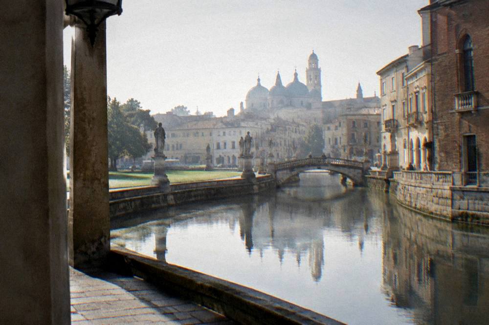 A quiet canal in Padua reflecting old stone buildings and a small footbridge