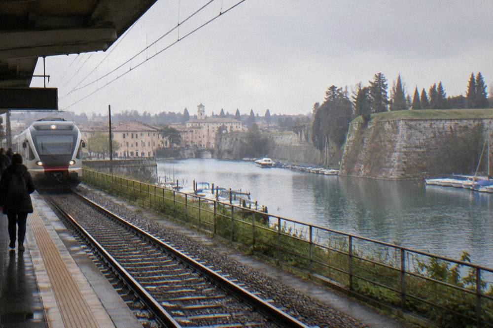 Regional train arriving at Peschiera del Garda station with the fortress town behind