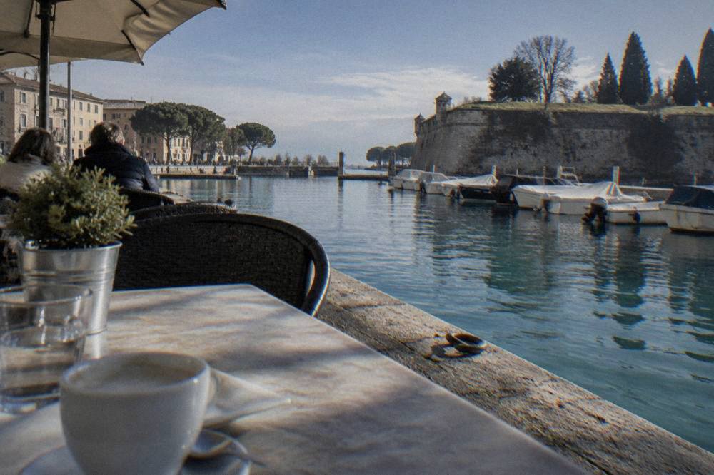 Restaurant tables beside a canal in Peschiera del Garda at lunchtime
