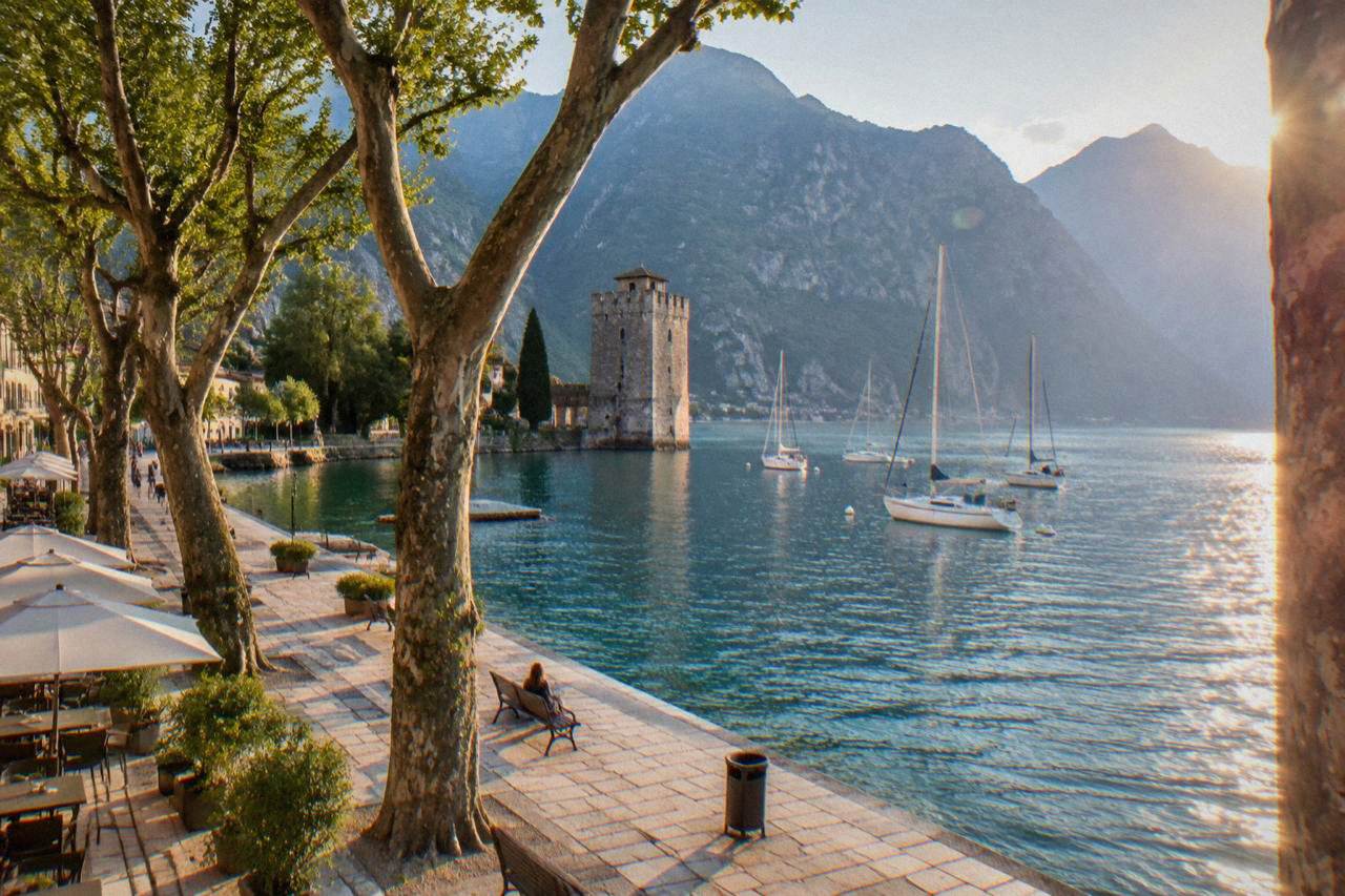 The waterfront promenade of Riva del Garda with the mountains of the northern lake rising behind the moored boats