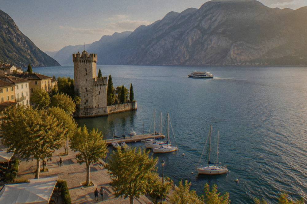 A passenger ferry crossing open water towards the mountain ridge at the top of Lake Garda