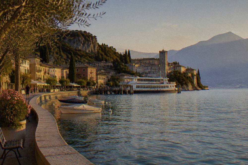 A ferry moored at a Lake Garda pier with the walled old town rising behind it