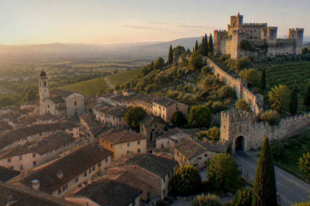 A view across a walled town's rooftops towards plains and distant hills