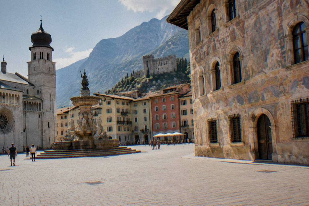 A frescoed Renaissance building facade on a sunny square in an Italian alpine town
