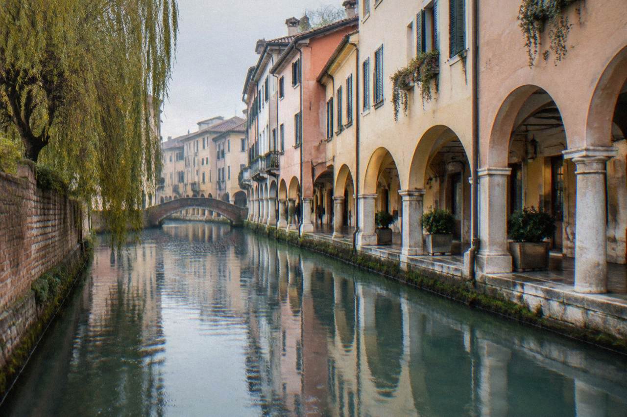 A quiet canal reflecting pastel painted houses under arcades in the centre of Treviso