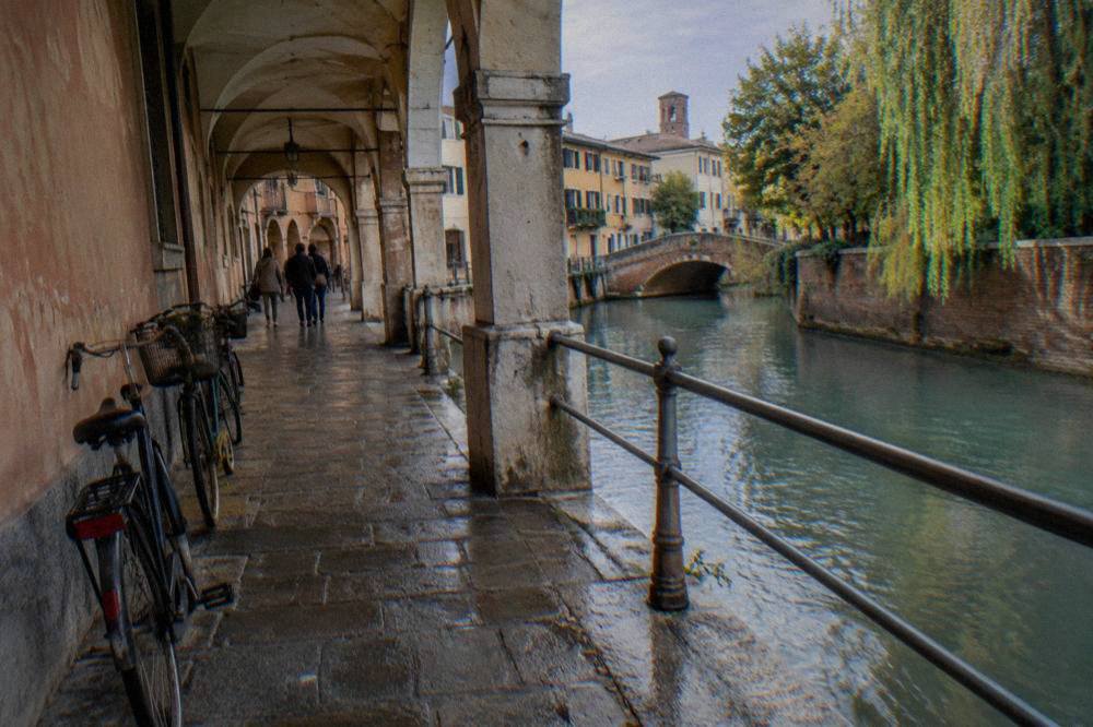 An arcaded shopping street in Treviso with bicycles parked against a painted wall