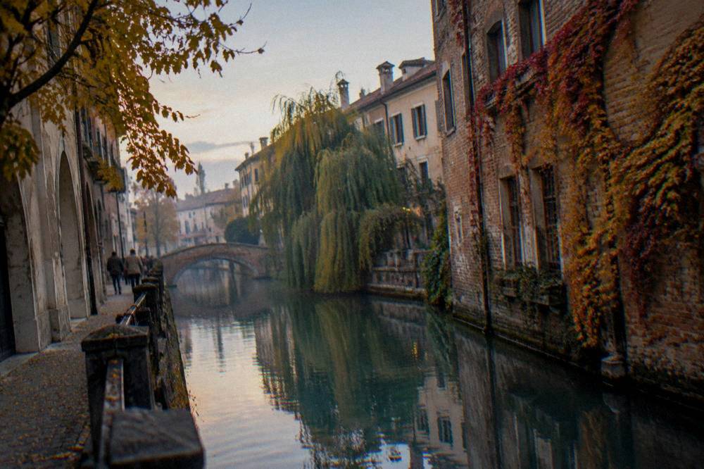 Autumn light on a canal between old brick buildings in a small Veneto city