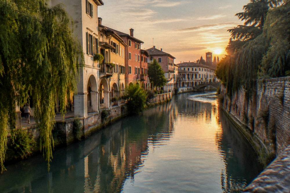 Evening light over rooftops and a river bend inside a walled Veneto town