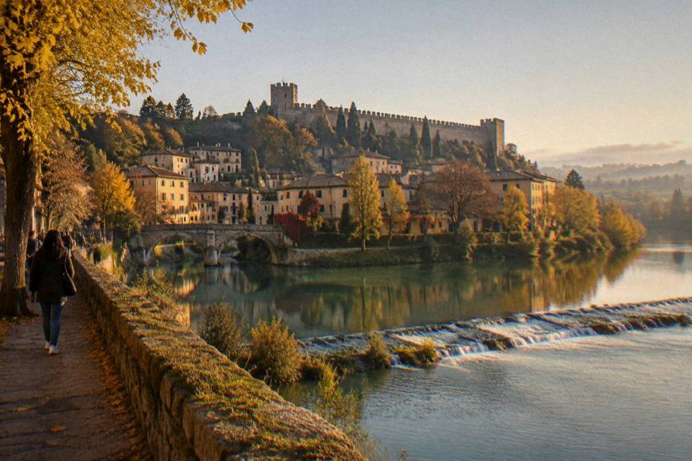 Autumn trees along a slow river with a stone weir and misty farmland beyond