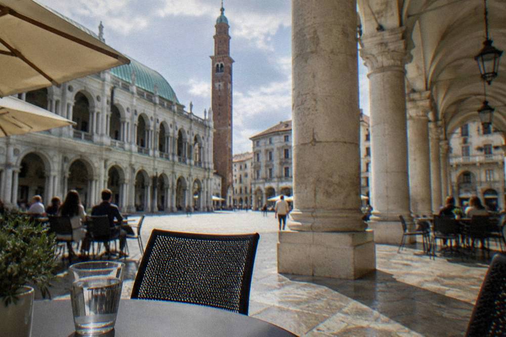 A covered stone loggia with arched walkways along an Italian city square