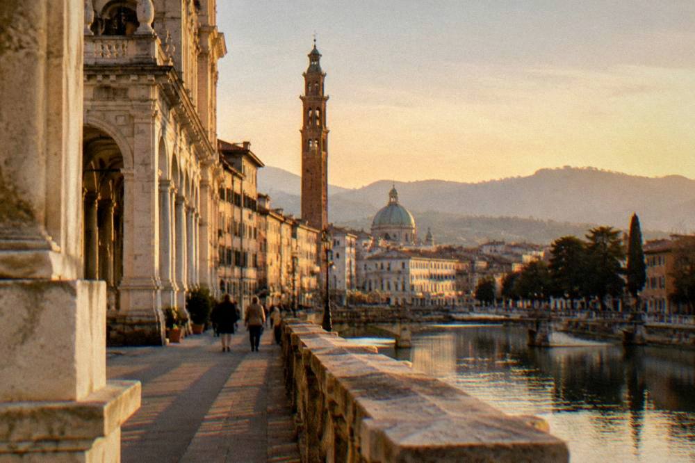 Golden late afternoon light on stone arcade buildings beside an Italian street