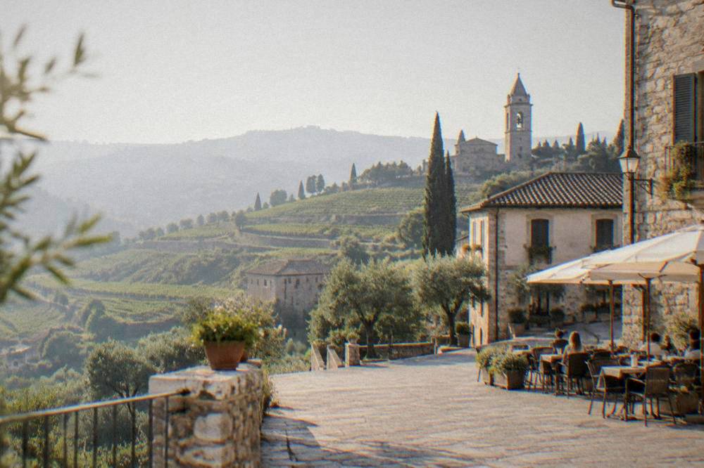 A sunlit piazza with cafe tables and historic buildings in late afternoon
