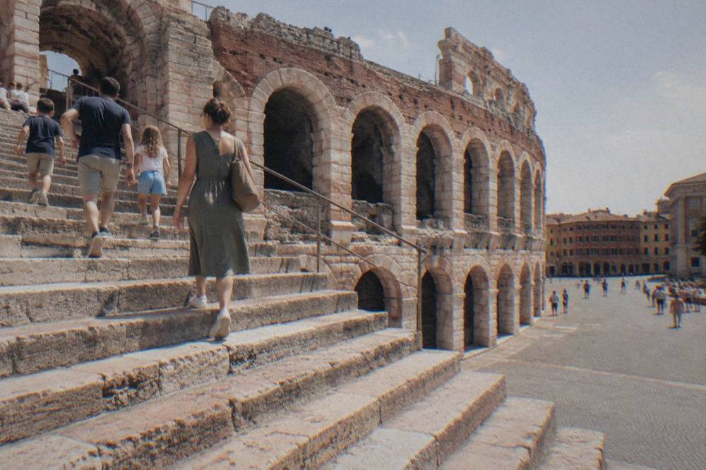 A family climbing the wide stone steps of the Verona Arena toward the upper tier