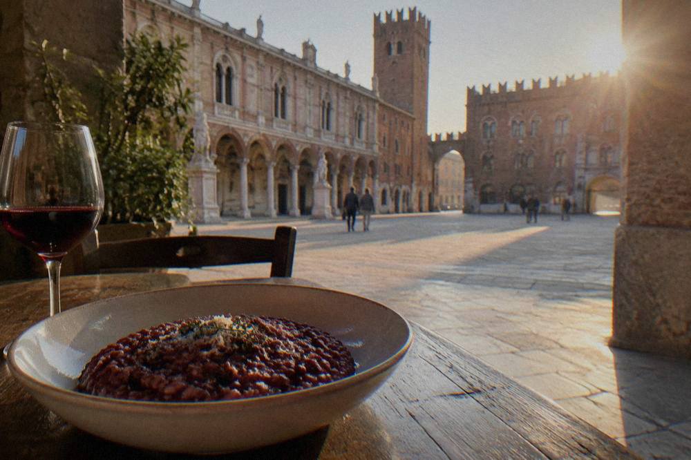 A bowl of dark red wine risotto served on a rustic wooden table