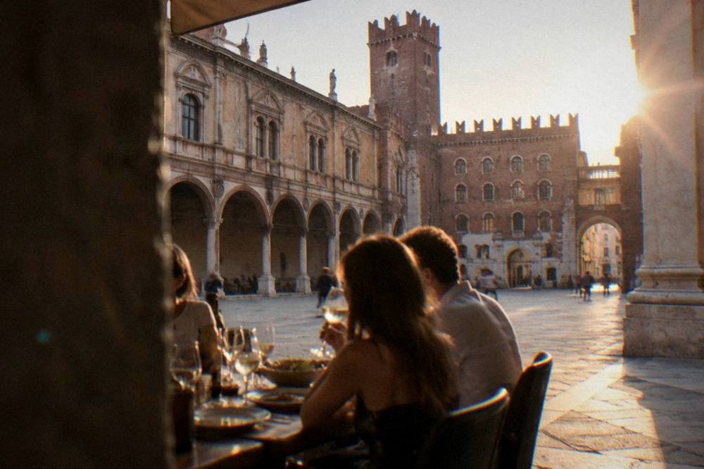 Friends sharing plates and wine at a long table in a warm evening restaurant