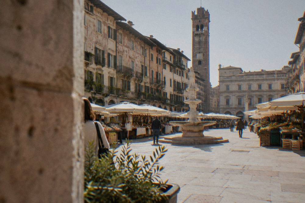 A quiet Piazza delle Erbe in morning light with market stalls and painted facades