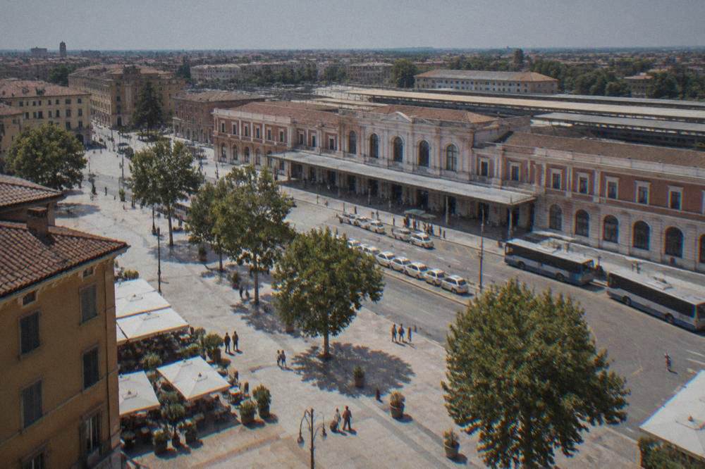 Sunlit square with old market buildings and cafe tables in a northern Italian city