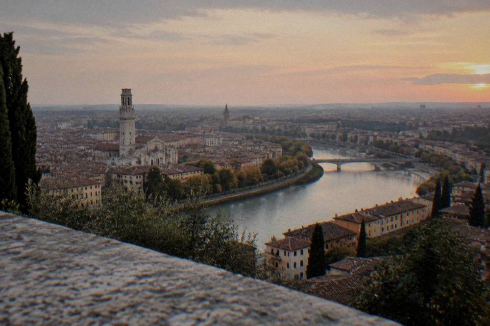 Rooftops and a river bend seen from a hilltop above an old Italian city at dusk