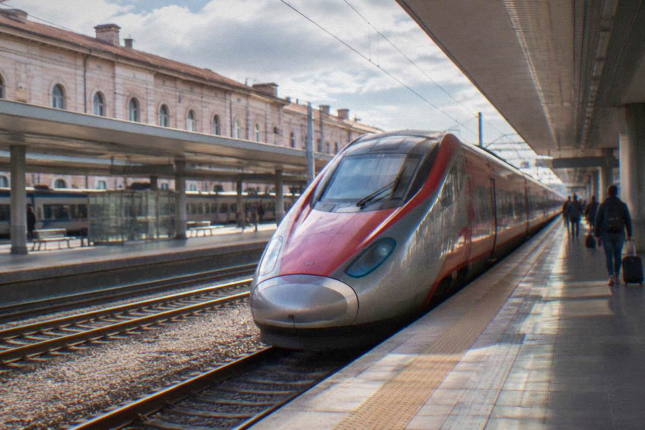 A high-speed train waiting at a platform inside a bright Italian railway station