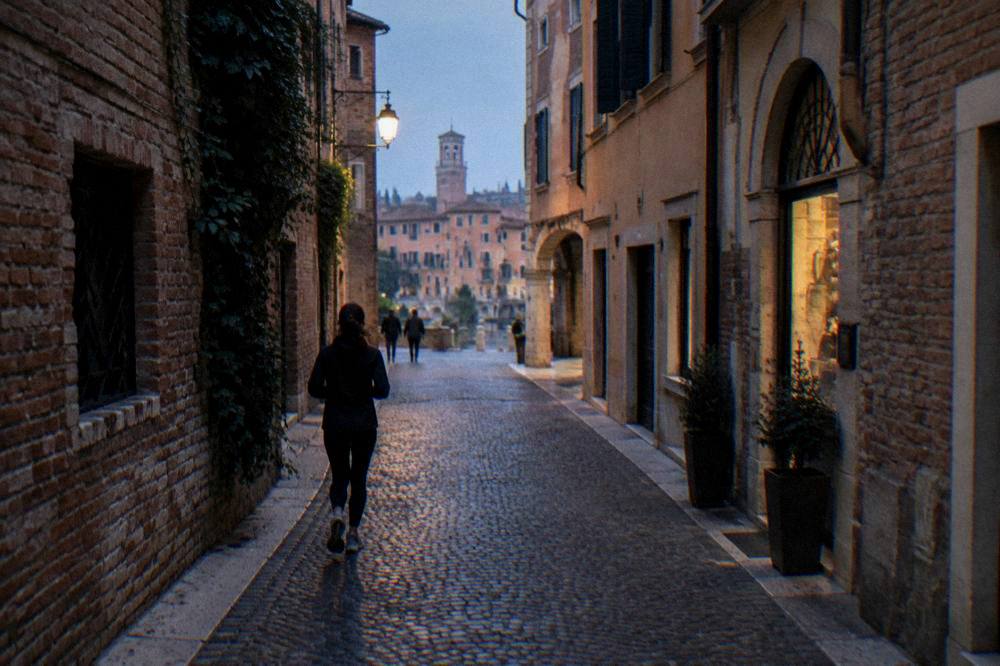 A narrow cobbled street in central Verona lined with old brick buildings and small shops