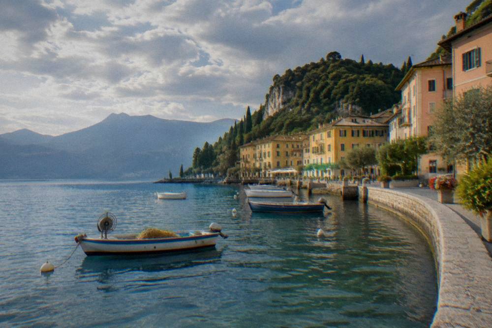 Fishing boats and pastel buildings along a Lake Garda waterfront in the late afternoon