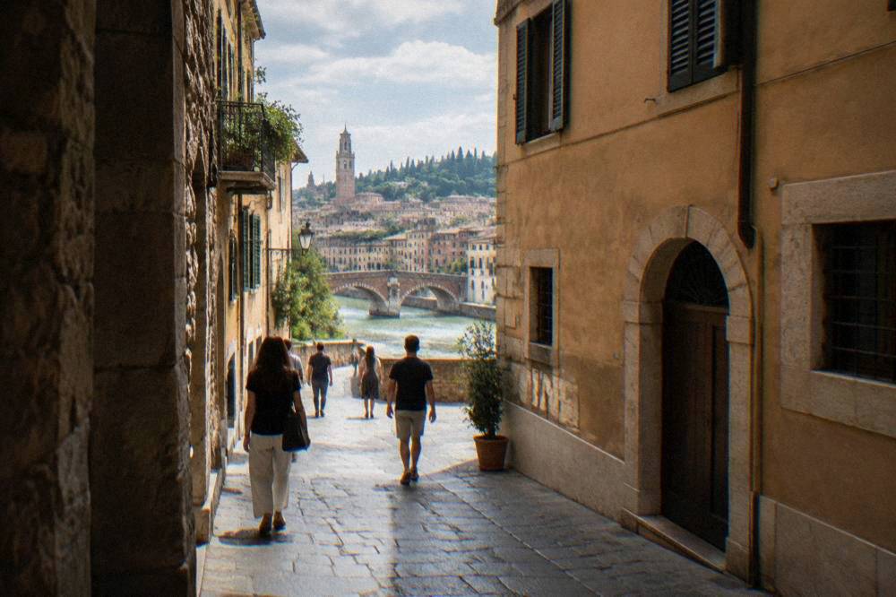 Pedestrians on a narrow cobbled street in Verona's old town lined with stone buildings