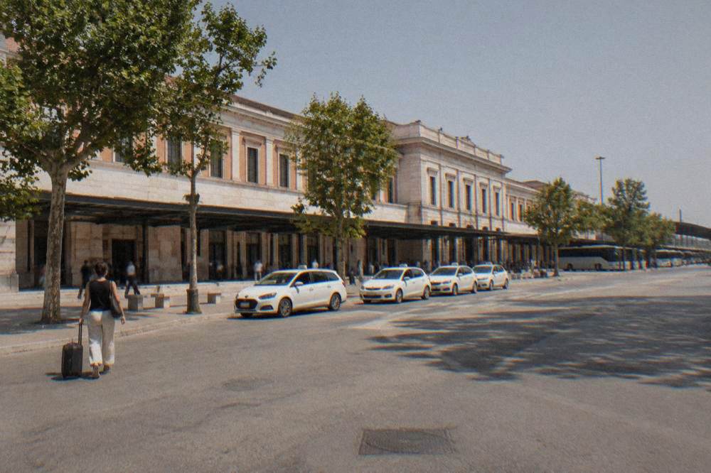 White licensed taxis lined up at a rank beside Verona Porta Nuova station