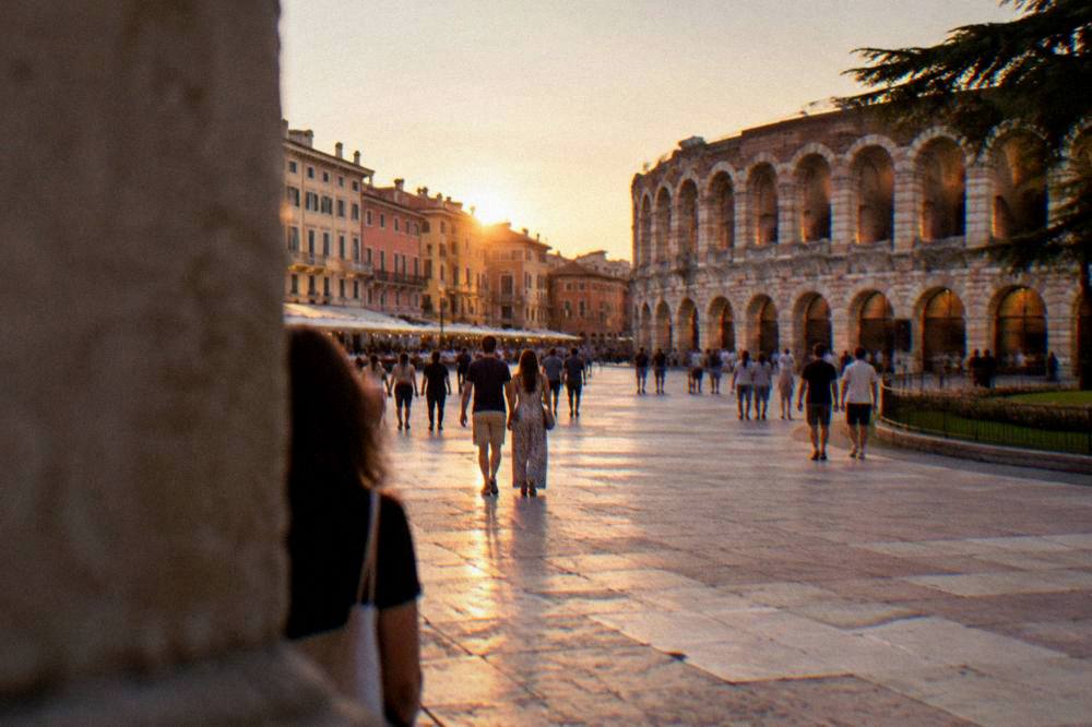 An evening crowd walking through Piazza Bra toward the lit Verona Arena
