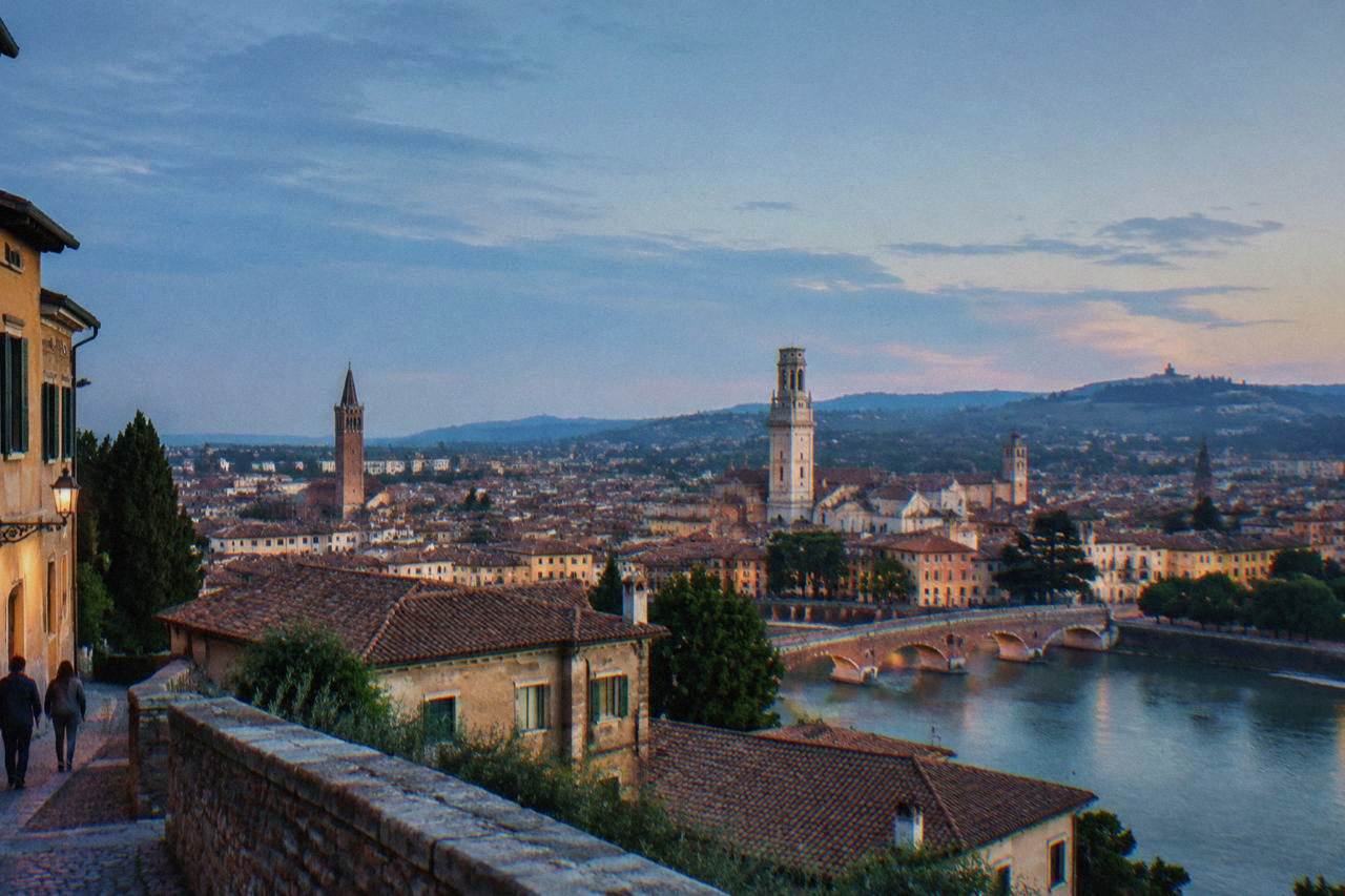 A view over red rooftops and church towers in Verona with hills in the distance