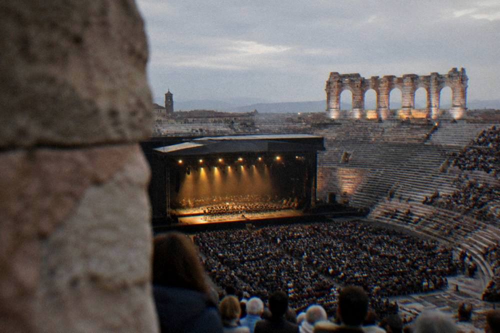 The Arena of Verona lit for an evening opera performance with the audience seated on stone steps